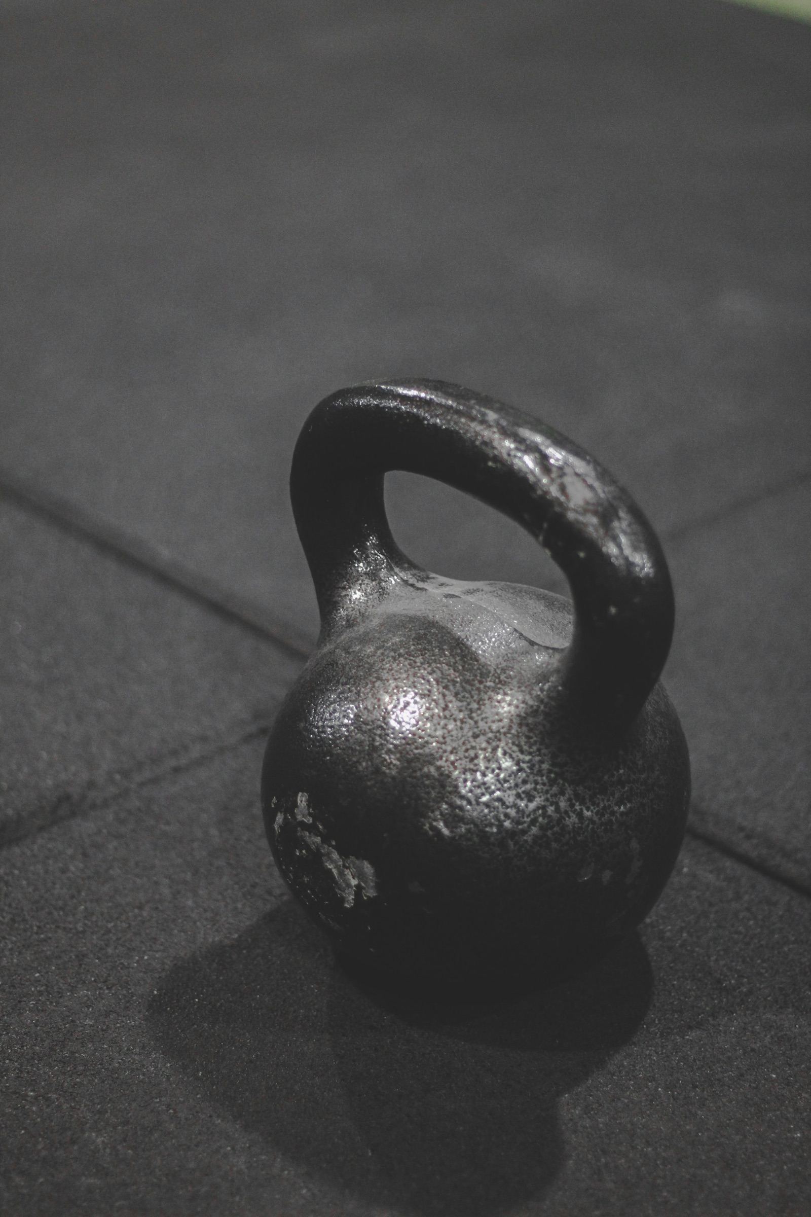 A kettlebell on a gym floor, in black and white